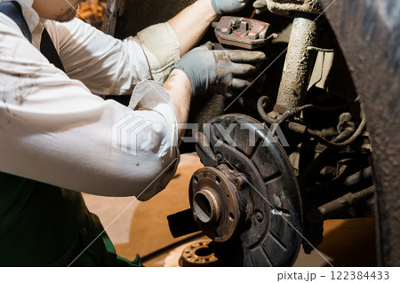 Mechanic Performing Brake Repair on a Vehicle in a Garage Mechanic Performing Brake Repair on a Vehicle in a Garage 122384433