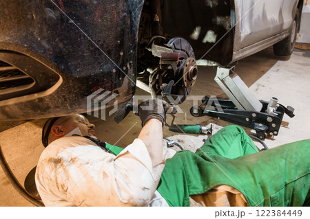 Mechanic Performing Brake Repair Under Car in Auto Shop 122384449