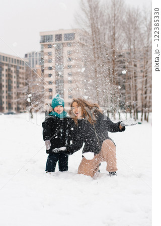 Happy family, mother and child are playing in the snow Happy family, mother and child are playing in the snow 122385330