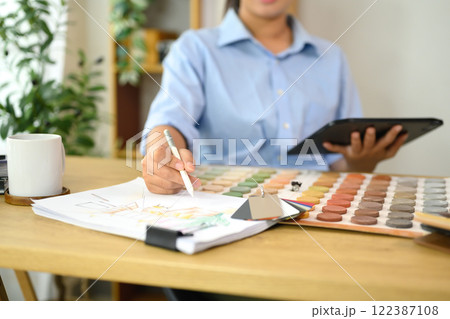 Interior designer selecting color samples while sketching design ideas on paper. Interior designer selecting color samples while sketching design ideas on paper. 122387108