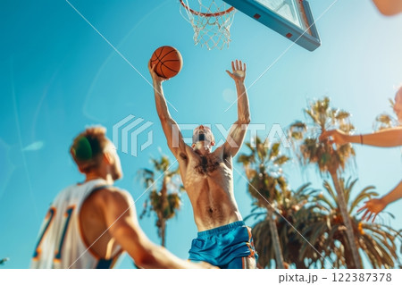 Young men having a friendly game of basketball in a serene and tropical location 122387378