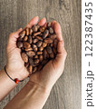 Female hands holding a handful of cocoa beans. Table top view 122387435