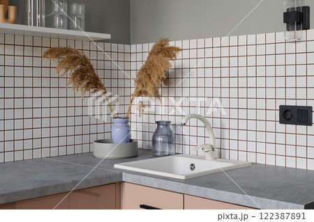 This modern kitchen corner features beige tiles and decorative elements, enhancing its style This modern kitchen corner features beige tiles and decorative elements, enhancing its style 122387891
