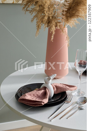An Elegant Table Setting Featuring a Decorative Bunny and a Modern Vase for Style 122387909