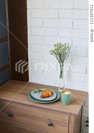 A Cozy and Inviting Breakfast Setting Featuring a Fresh Croissant and Beautiful Flowers 122387911