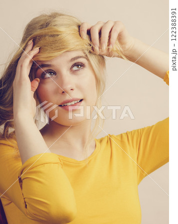 Girl making a fringe from her long blonde hair Girl making a fringe from her long blonde hair 122388391