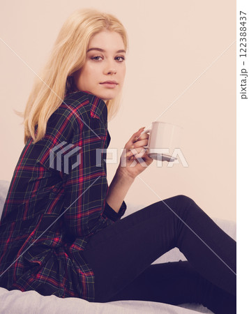 Teenage woman sitting on sofa with mug 122388437