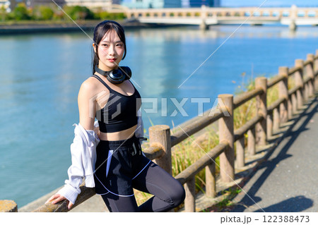 川沿いで歩く途中に座ってポーズをとるかっこいい女性　ポージング　ダイエット　散歩　運動　 122388473