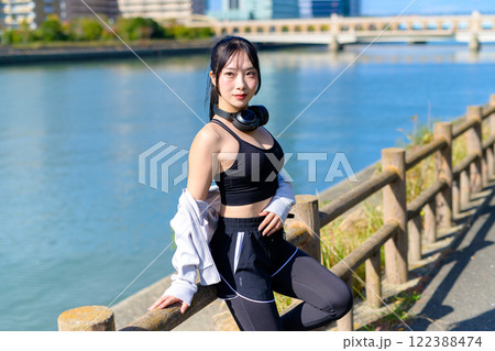 川沿いで歩く途中に座ってポーズをとるかっこいい女性　ポージング　ダイエット　散歩　運動　 122388474