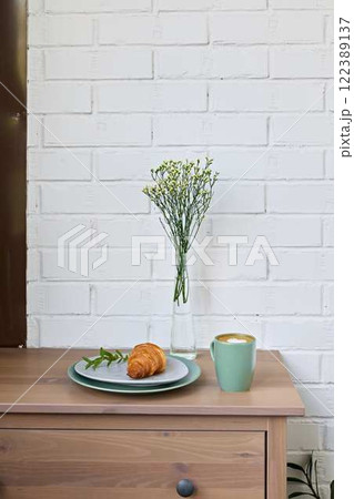 A Cozy Breakfast Setting featuring a Croissant, Fresh Flowers, and a Beautiful Atmosphere A Cozy Breakfast Setting featuring a Croissant, Fresh Flowers, and a Beautiful Atmosphere 122389137