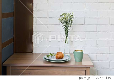 A Cozy Breakfast Setting Featuring a Flaky Croissant Accompanied by Beautiful, Colorful Flowers 122389139