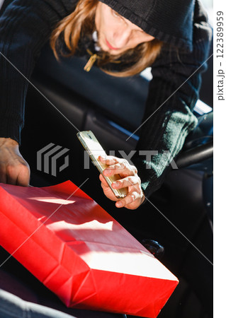 Burglar thief stealing smartphone and bag from car Burglar thief stealing smartphone and bag from car 122389959