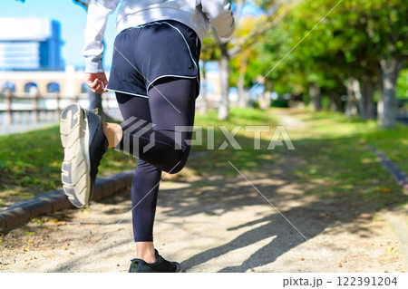 秋の公園の街路樹の道をジョギングする若い女性の後ろ姿　ダイエット　ボディメイク　下半身 122391204