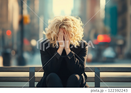 Young woman with curly hair sitting on a bench in a bustling city, expressing emotion Young woman with curly hair sitting on a bench in a bustling city, expressing emotion 122392243