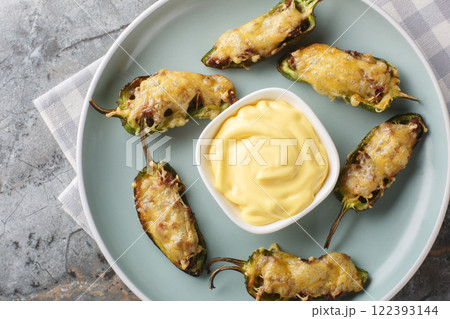 Mexican jalapeno peppers baked with ground beef and cheese served with dipping sauce close-up in a plate. Horizontal top view 122393144