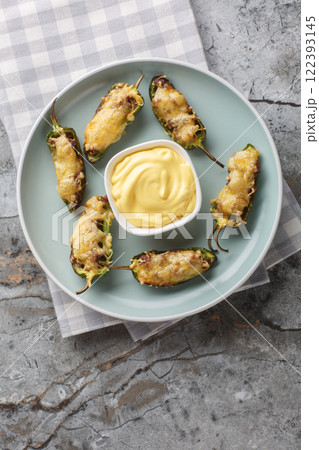 Baked jalapeno peppers with ground beef and cheese served with sauce close-up in a plate. Vertical top view 122393145