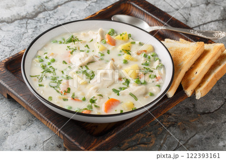 Comfort chicken pot pie soup with potatoes, carrots and green peas in a spicy creamy broth close-up in a bowl. Horizontal Comfort chicken pot pie soup with potatoes, carrots and green peas in a spicy creamy broth close-up in a bowl. Horizontal 122393161