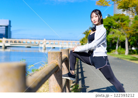 川沿いの柵で脚のストレッチをするかっこいい女性　歩く　ダイエット　散歩　運動　 122393212