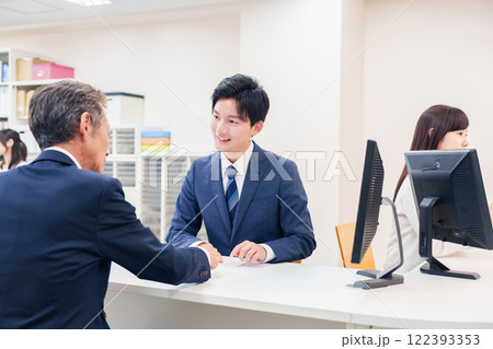 窓口で高齢者の来客の対応をする男性 122393353