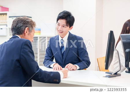 窓口で高齢者の来客の対応をする男性 122393355