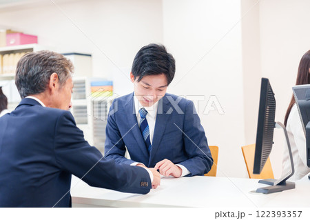 窓口で高齢者の来客の対応をする男性 122393357