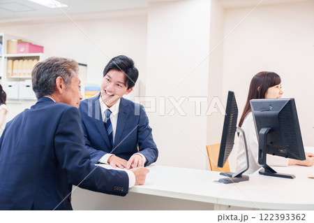 窓口で高齢者の来客の対応をする男性 122393362