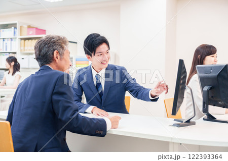 窓口で高齢者の来客の対応をする男性 122393364