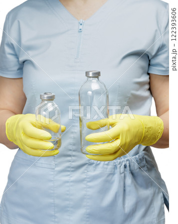 Female physician in latex gloves holding bottles for liquid medicine. 122393606