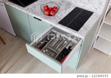 This is a modern kitchen drawer that contains cutlery alongside fresh, vibrant apples This is a modern kitchen drawer that contains cutlery alongside fresh, vibrant apples 122394155