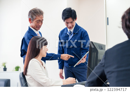 オフィスで話す作業服の人とスーツの女性 オフィスで話す作業服の人とスーツの女性 122394717