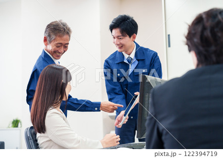 オフィスで話す作業服の人とスーツの女性 オフィスで話す作業服の人とスーツの女性 122394719