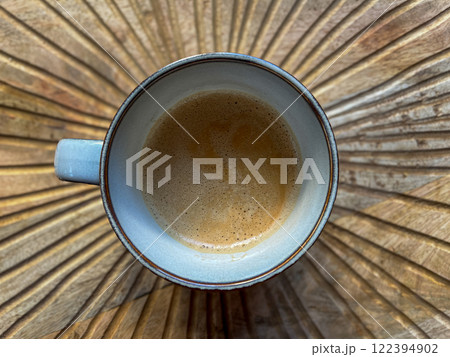 A cup of coffee, viewed from above. It stands on a wooden surface with carved lines. A cup of coffee, viewed from above. It stands on a wooden surface with carved lines. 122394902