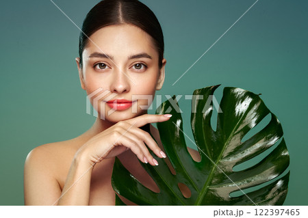 Close up woman face with green exotic leaf Close up woman face with green exotic leaf 122397465