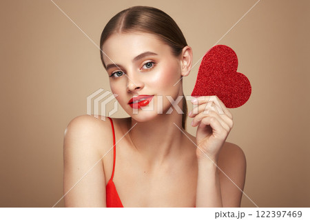 Beautiful woman holding an artificial red heart 122397469