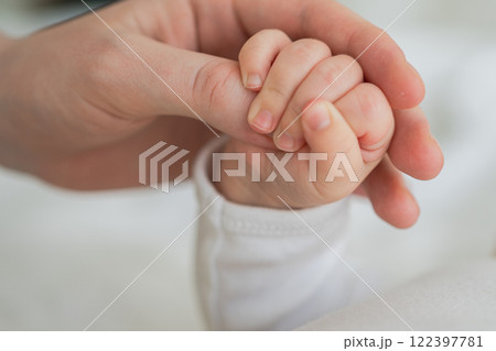 Happy family. Tiny newborn infant baby little hand on mother hand palm. Newborn baby holding parent finger after birth. Mom baby at home. Support protection of new life. Handle with care Happy family. Tiny newborn infant baby little hand on mother hand palm. Newborn baby holding parent finger after birth. Mom baby at home. Support protection of new life. Handle with care 122397781