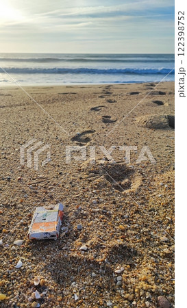 Garbage, plastic, and wastes on the beach of Portugal. Sand beaches polluted with pieces of plastic, cigarette pack 122398752