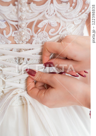Bridal Gown Lacing Technique at a Wedding Preparation in the Afternoon Sunlight. 122398838