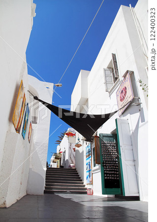 Thira, Santorini island, Greece. Picturesque view of the street of ancient Thira. Traditional white houses against blue sky. 122400323