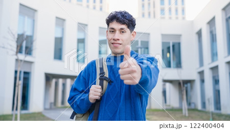 Smiling university student gesturing thumbs up outdoors Smiling university student gesturing thumbs up outdoors 122400404
