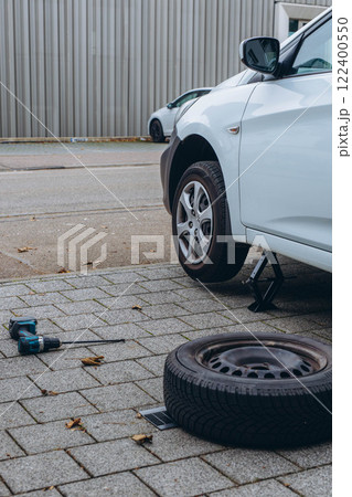 Man changing his car's tire with a wrench, replacing it with winter tires for the season Man changing his car's tire with a wrench, replacing it with winter tires for the season 122400550
