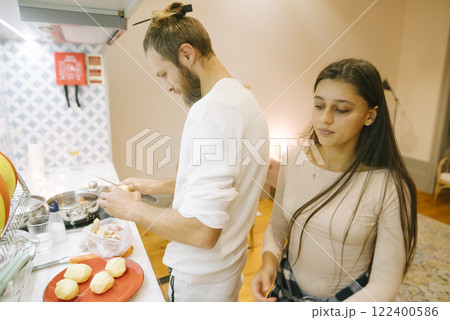 A couple happily cooking together in a beautifully modern kitchen with natural sunlight 122400586