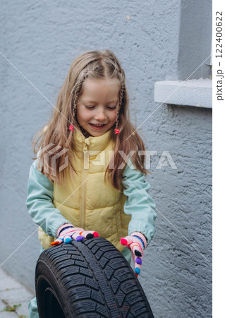 A daughter helps her father change tires on the car, sharing a bonding moment during the task 122400622