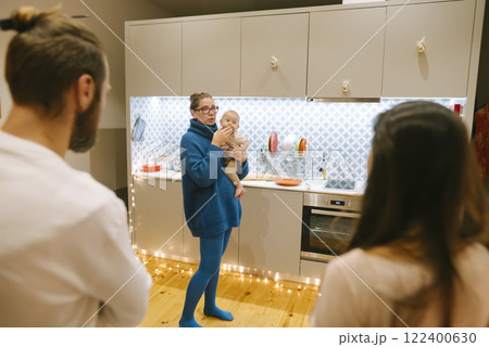 A cozy family gathering featuring a baby is taking place in a modern kitchen setting 122400630