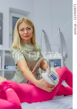 Young woman in a pink suit receiving LPG massage at a professional cosmetology clinic. 122400671
