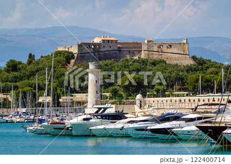 Castle and port with boats and lighthouse in Antibes, summer dayat the sea, white blue clouds Castle and port with boats and lighthouse in Antibes, summer dayat the sea, white blue clouds 122400714
