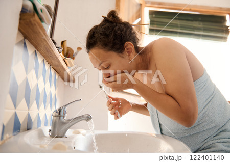Young woman rinsing her mouth after brushing her teeth in the morning 122401140
