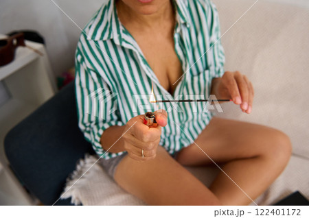 Person outdoors lighting an incense stick with focus on their hands and styler Person outdoors lighting an incense stick with focus on their hands and styler 122401172
