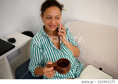 Woman enjoying a conversation while holding coffee in a relaxed environment Woman enjoying a conversation while holding coffee in a relaxed environment 122401173