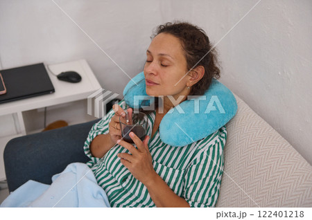 Woman relaxing with tea and neck pillow enjoying a calm moment at home Woman relaxing with tea and neck pillow enjoying a calm moment at home 122401218