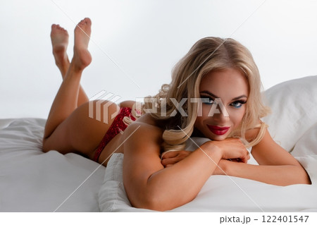 Woman poses in fitness lingerie on bed showcasing her athletic physique 122401547
